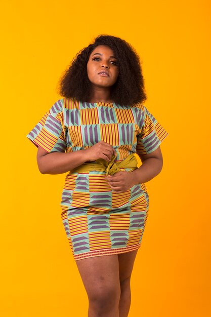 Young beautiful african american girl with an afro hairstyle. Portrait on yellow background. Girl