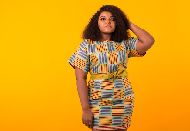 Young beautiful african american girl with an afro hairstyle. Portrait on yellow background with