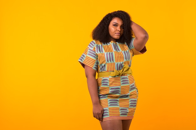 Young beautiful african american girl with an afro hairstyle. Portrait on yellow background with