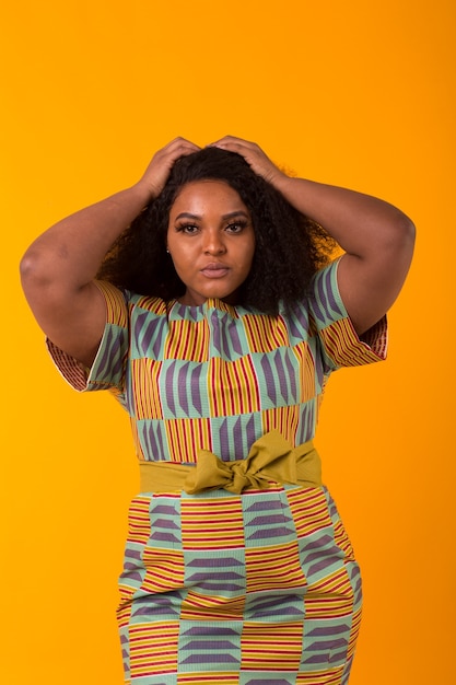 Young beautiful african american girl with an afro hairstyle. Portrait on yellow background.