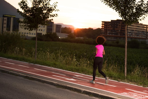 young beautiful African American woman enjoys running outside beautiful summer evening in the city