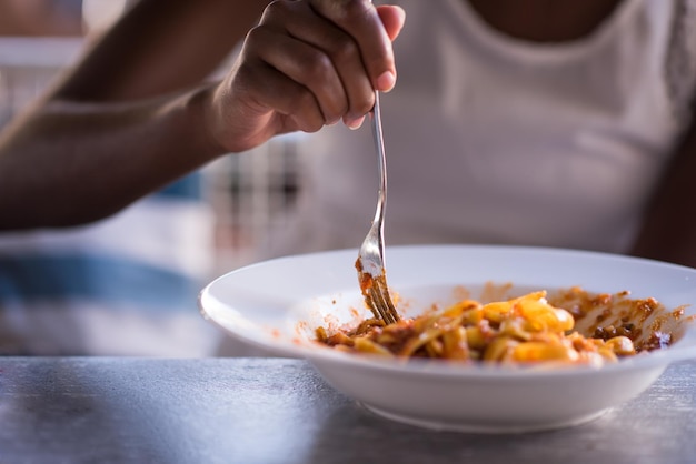 young beautiful African American woman enjoys while eating delicious pasta