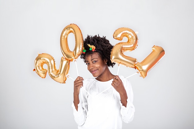 Young beautiful African with reindeer horns on her head holding balloons