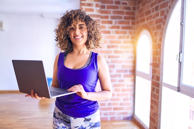 Young beautiful arab sportwoman smiling happy Standing using laptop before class of yoga at gym