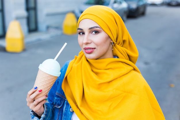 Young beautiful arab woman in hijab drinking cooling cocktail outdoor.