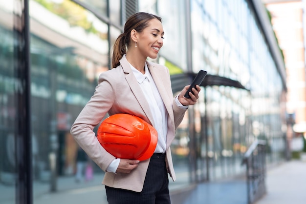 Young beautiful architect girl smiling happy standing and using phone