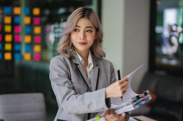 Young beautiful Asian business woman hold paper account documents informal spreadsheet financial