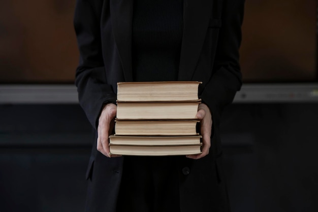 a young beautiful asian female teacher in the school holding stack of books before class