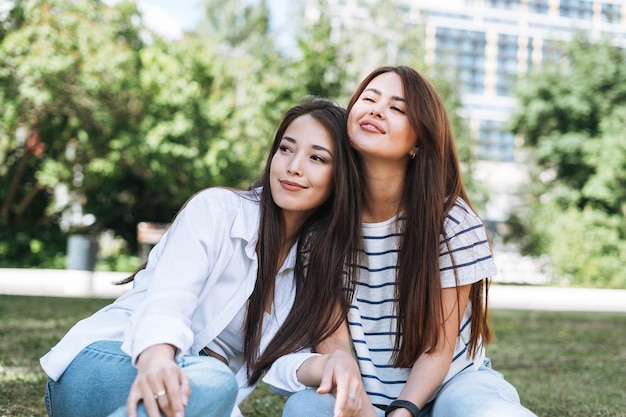 Young beautiful asian girls with long hair in casual clothes friends having fun in city park