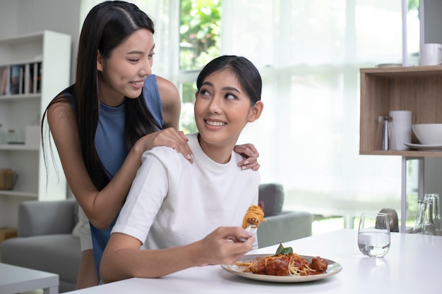 Young beautiful Asian lesbian couple lifestyle living concept Happy LGBT couple having breakfast together in the kitchen