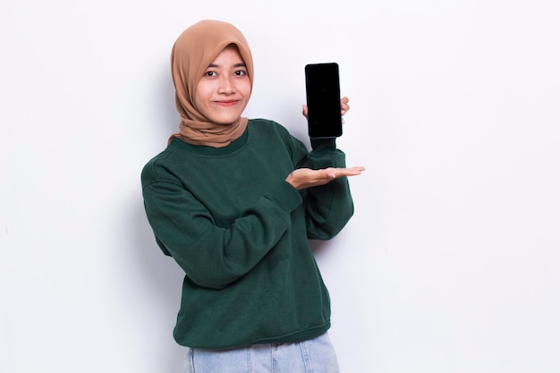 young beautiful asian muslim woman demonstrating mobile cell phone isolated on white background