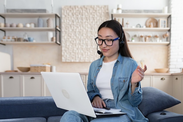 Young beautiful asian teacher in glasses teaching students remotely woman using headset and laptop