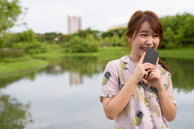 Young beautiful Asian tourist woman relaxing at the park