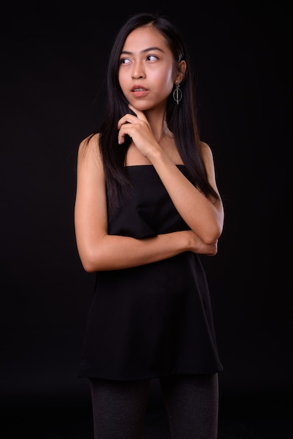  young beautiful Asian woman against black wall