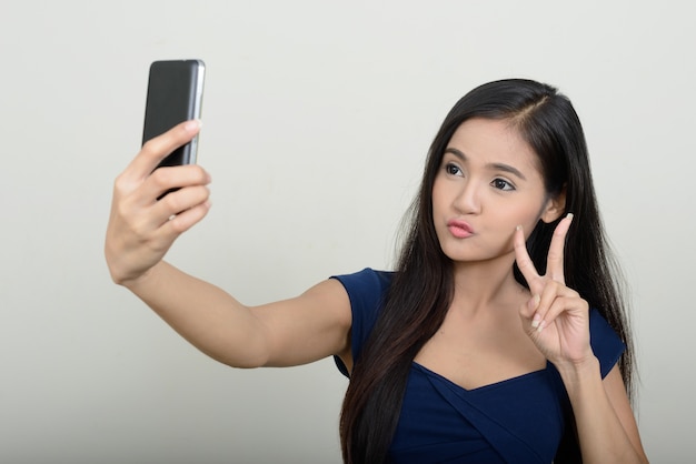 young beautiful Asian woman against white wall