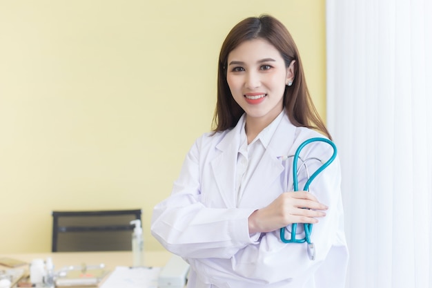 Young beautiful  Asian woman doctor Standing with arms crossed happy and smile in hospital