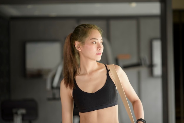 A young beautiful Asian woman is standing in the gym , smiling after workout. Fitness and health concept