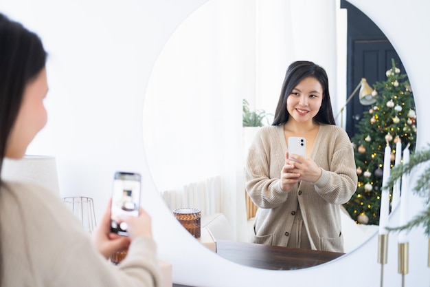 Young beautiful asian woman looking at her reflection in the mirror, taking selfie