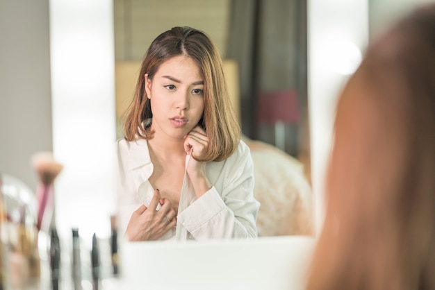 Young Beautiful Asian Woman making make-up near mirror