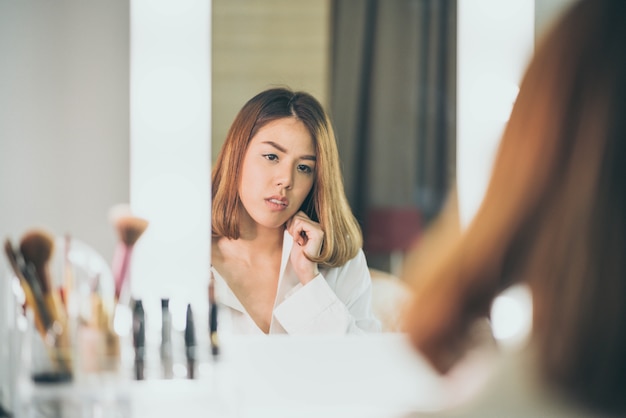 Young Beautiful Asian Woman making make-up near mirror