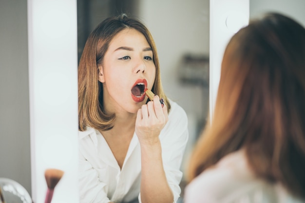 Young Beautiful Asian Woman making make-up near mirror