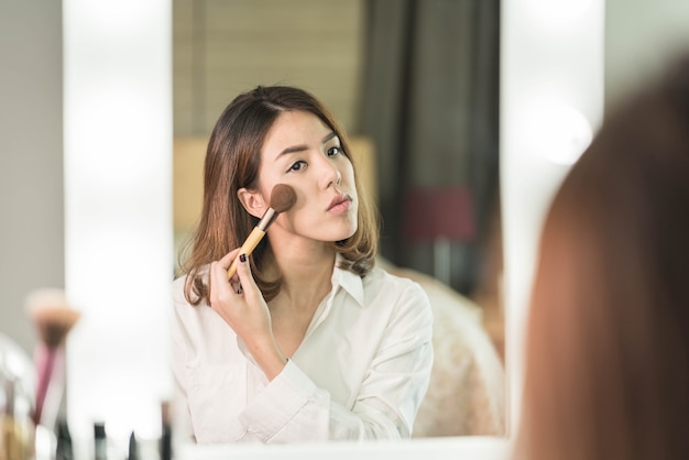 Young Beautiful Asian Woman making make-up near mirror