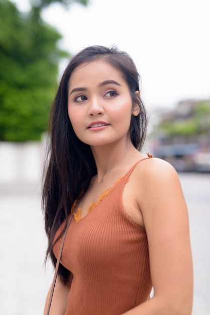 Young beautiful Asian woman thinking in the streets outdoors