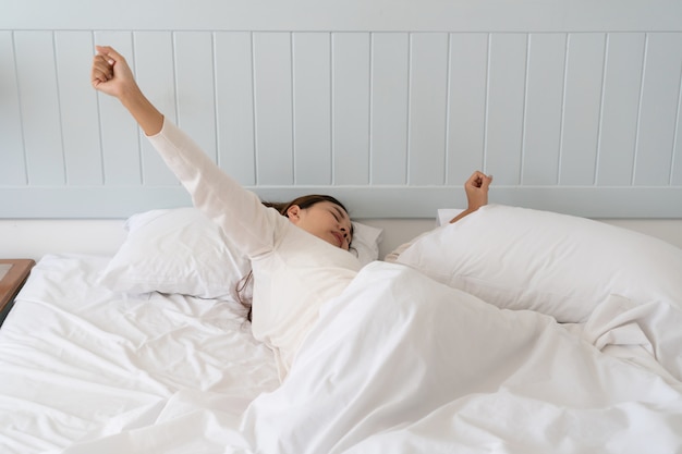 Young beautiful Asian woman too lazy to get out of bed in the morning.