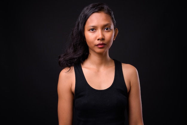  young beautiful Asian woman with nose ring against black wall