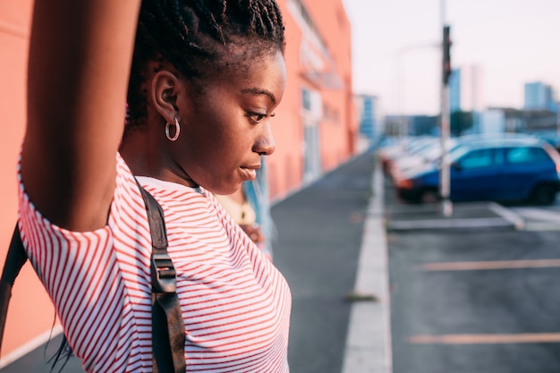 Young beautiful black woman alone outdoor backlight pensive touching hair