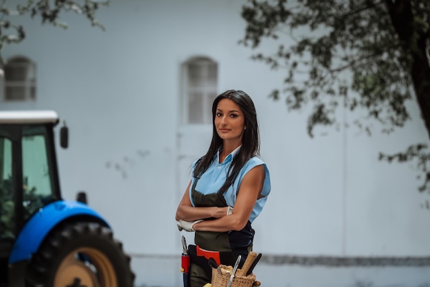 A young and beautiful blackhaired farmer poses confidently with her arms crossed emanating strength