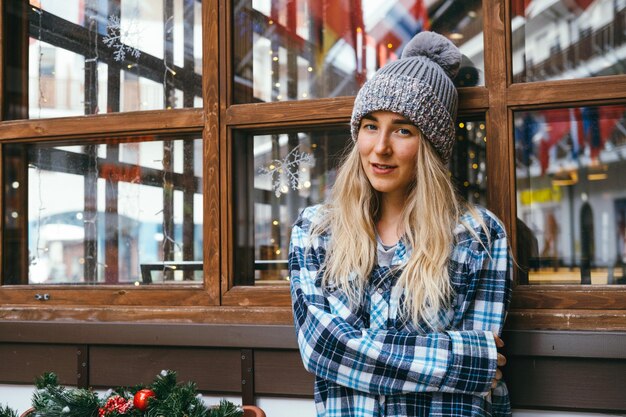 Young beautiful blonde hipster woman on the background of a wooden house Christmas and New Year trav