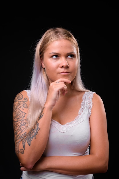 Young beautiful blonde woman on black wall