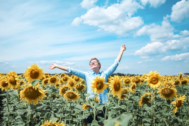 Young beautiful blonde woman standing in sunflower field