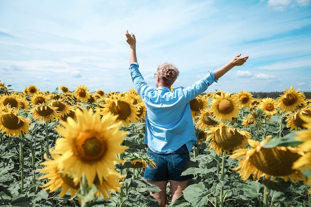 Young beautiful blonde woman standing in sunflower field