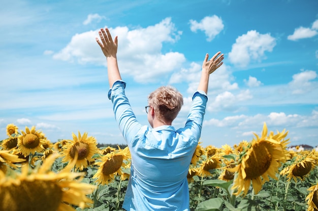 Young beautiful blonde woman standing in sunflower field