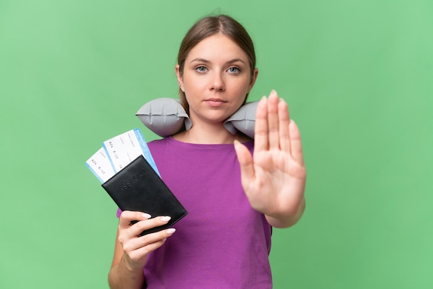 Young beautiful blonde woman with Inflatable travel Pillow over isolated background making stop gesture