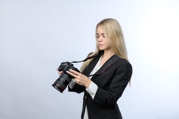 Young beautiful blonde woman with modern DSLR cameras looking to camera screen on white background