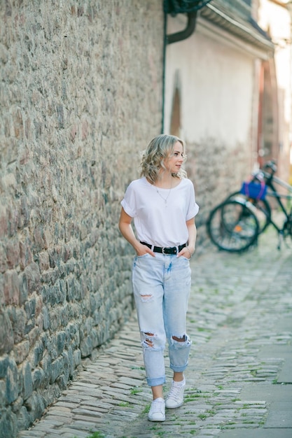 Young beautiful blueeyed blonde in the center of a European city Portrait of a stylish model in casual clothes Happy youth