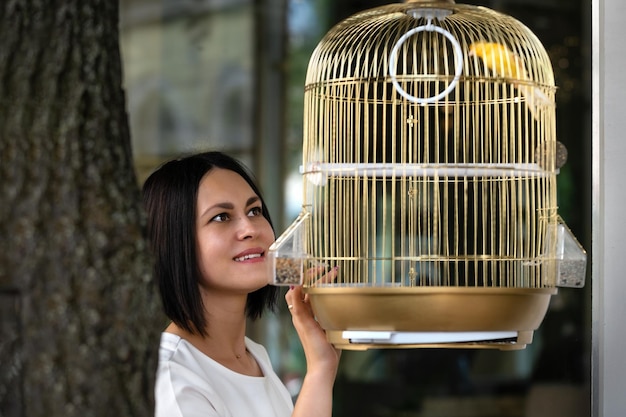 young beautiful brunette woman in a bar admiring a canary bird in a golden cage