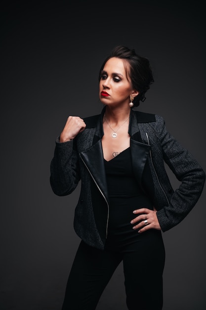 Young beautiful brunette woman with red lips on black background