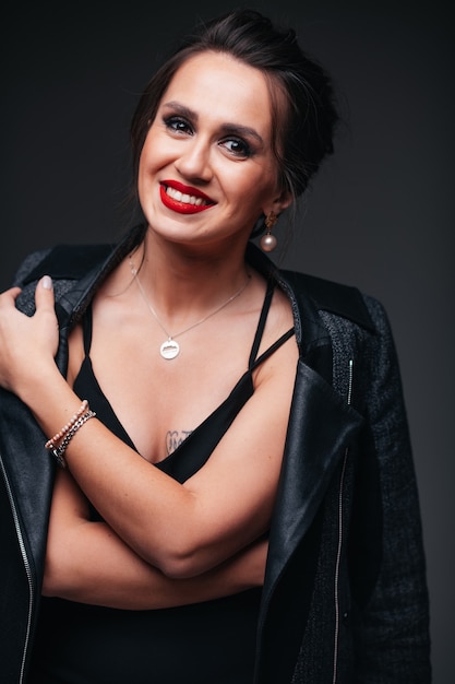 Young beautiful brunette woman with red lips on black background