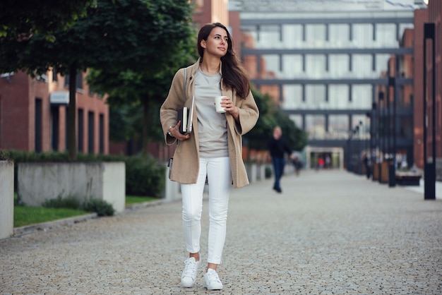 Young beautiful business woman at casual clothes near office centre with cup of coffee lunch break