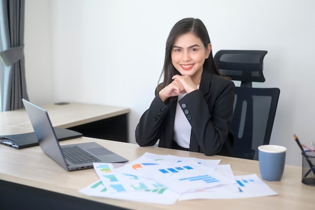 Young beautiful business woman working on laptop with documents in modern office