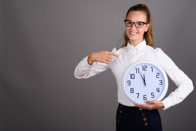 Young beautiful businesswoman against gray background