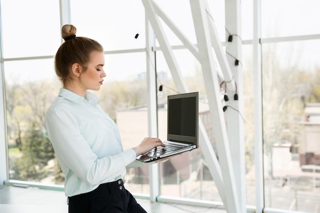 Young beautiful businesswoman works in the office with a laptop. Success concept