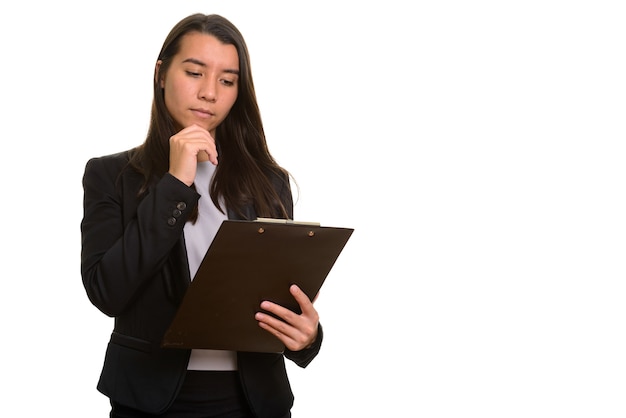 Young beautiful Caucasian businesswoman reading on clipboard while thinking