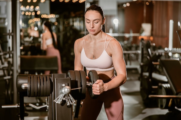 Young beautiful caucasian fit strong woman is doing exercises in gym