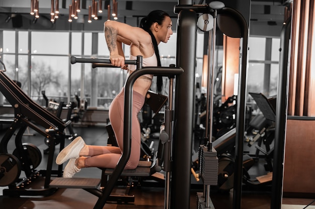 Young beautiful caucasian fit strong woman is doing exercises in gym