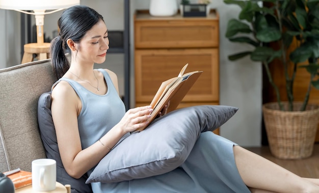 Young beautiful caucasian woman relaxing while reading a book on sofa at home